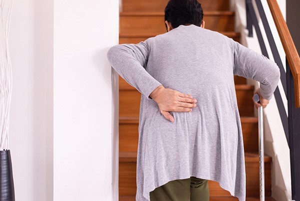Person with back pain suffering getting up stairs